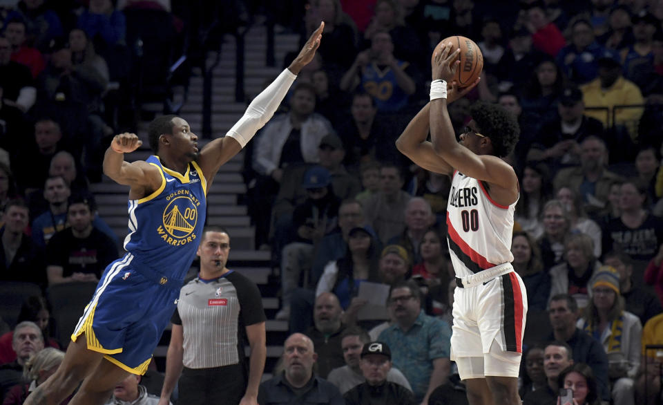 Portland Trail Blazers guard Scoot Henderson, right, shoots over Golden State Warriors forward Jonathan Kuminga, left, during the first half of an NBA basketball game in Portland, Ore., Thursday, April 11, 2024. (AP Photo/Steve Dykes)