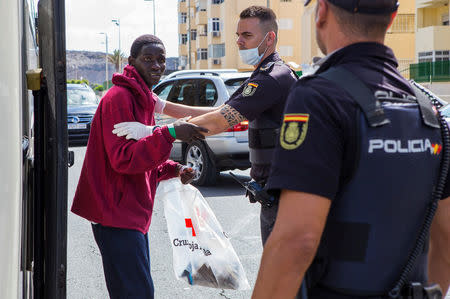 A migrant, part of a group intercepted aboard a make-shift boat at sea south of Spain's Canary Islands, is escorted by Spanish police after arriving in Maspalomas, on the island of Gran Canaria, Spain, June 23, 2018. REUTERS/Borja Suarez