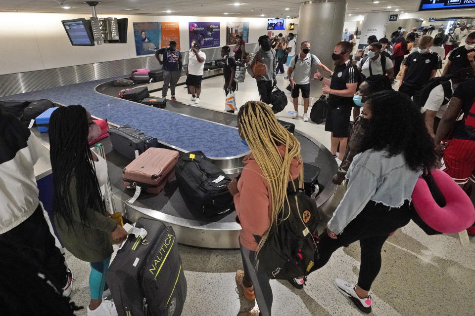 FILE - In this May 28, 2021 file photo, travelers wait for their luggage at a baggage carousel at Miami International Airport in Miami. The airline industry’s recovery from the pandemic passed a milestone as more than 2 million people streamed through U.S. airport security checkpoints on Friday for the first time since early March 2020. (AP Photo/Wilfredo Lee, File)