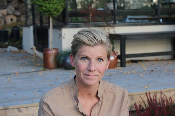 Woman with short hair smiling, facing the camera, wearing a casual shirt outside