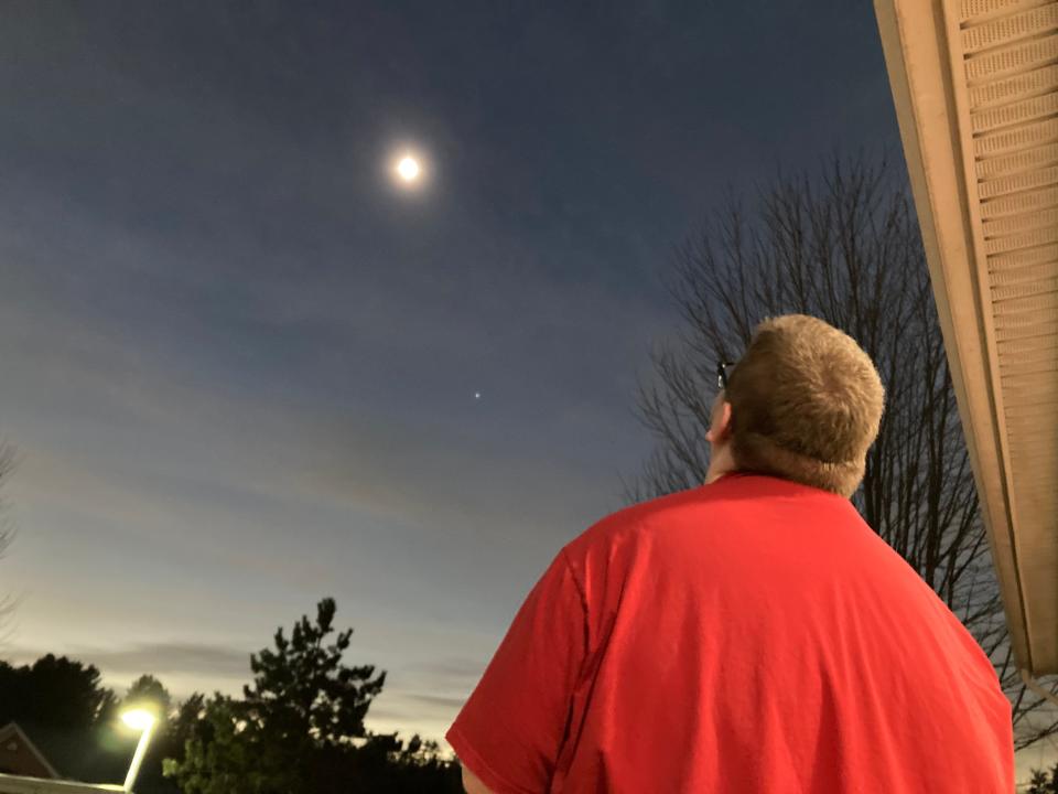 Skyler Gillilan, a clerk at Simon's Store & Deli in St. George, Vermont, looks Monday, April 8, 2024 at a total eclipse that settled over northern Vermont.