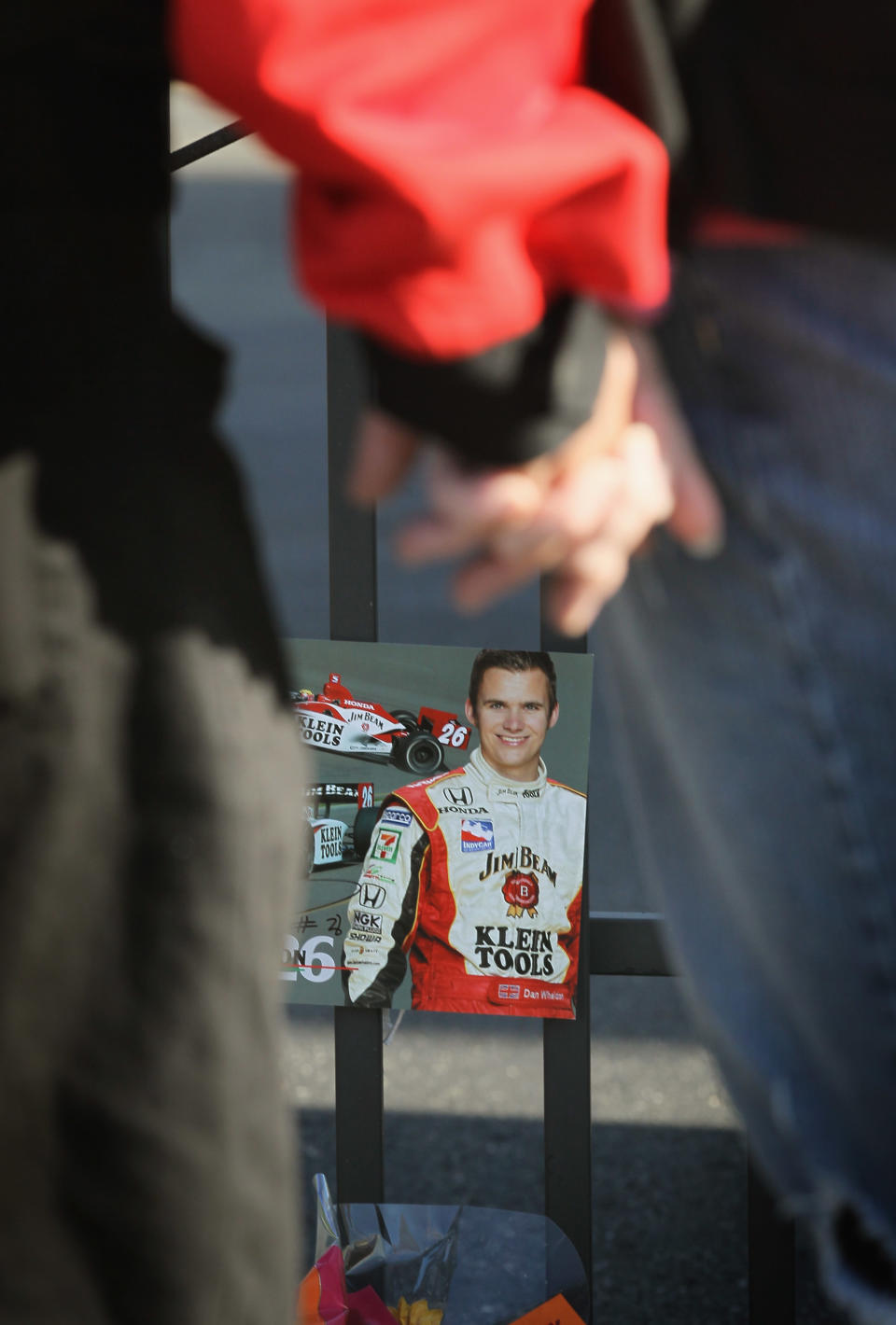 INDIANAPOLIS, IN - OCTOBER 17: Fans look over tributes to two-time Indianapolis 500 winner Dan Wheldon which have been left at a memorial at the gate of the Indianapolis Motor Speedway on October 17, 2011 in Indianapolis, Indiana. Wheldon, winner of the 2011 Indy 500, was killed in a crash yesterday at the Izod IndyCar series season finale at Las Vegas Motor Speedway. (Photo by Scott Olson/Getty Images)