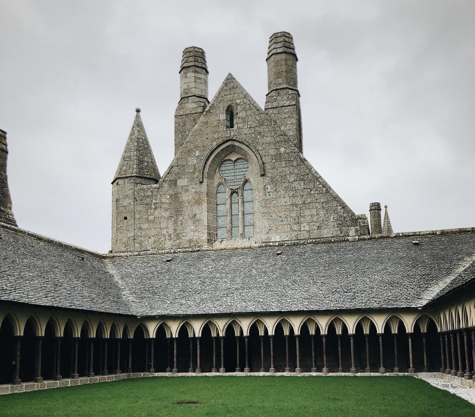 Check out these unique facts about the Mont-Saint-Michel in Normandy. 
Pictured: A large gothic building with a green lawn in Mount-Saint-Michel