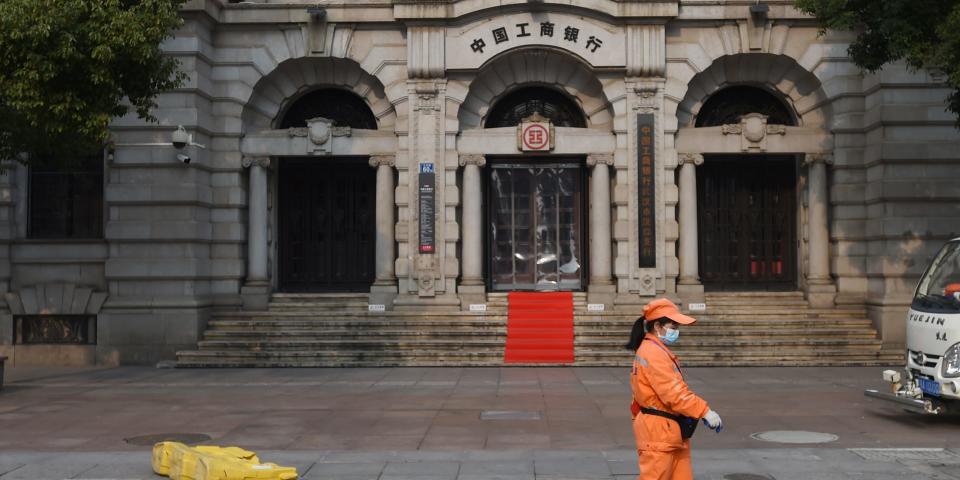 FILE PHOTO: A sanitation worker wearing a face mask walks past a branch of Industrial and Commercial Bank of China (ICBC) in Wuhan, the epicentre of the novel coronavirus outbreak, Hubei province, China February 25, 2020. REUTERS/Stringer  