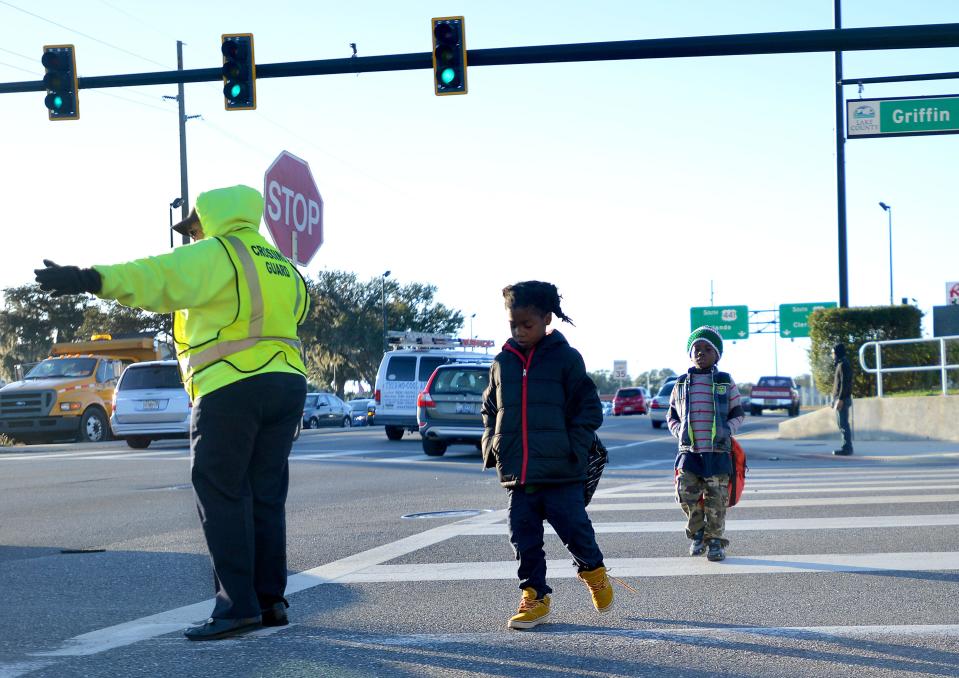 Crossing guard Angel Miller stops traffic as young children bundled up in jackets and coats cross the street on their way to school on Monday, Jan. 09, 2017 in Leesburg.