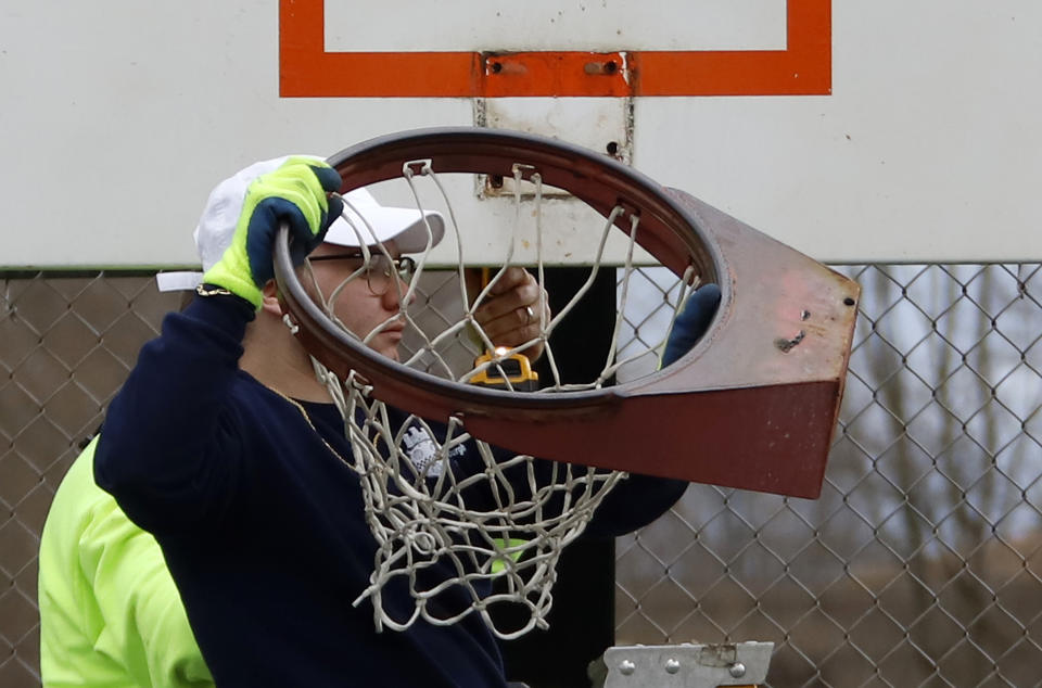 A Pittsburgh public works employee removes a basketball rim from a court Monday because people were not following social distancing rules while using the courts during the weekend. (AP Photo/Gene J. Puskar)