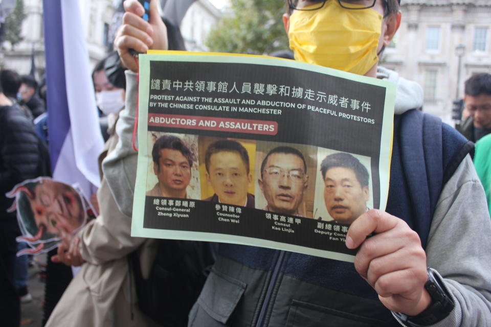 有出席者手持的單張，印上懷疑涉事的 4 名曼城使館人員肖像。
