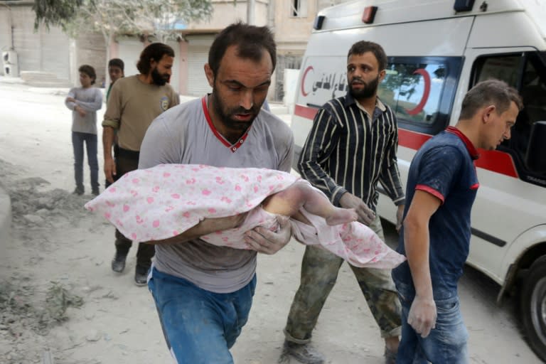 A Syrian man carries the body of an infant retrieved from under the rubble of a building following air raids in Aleppo on September 23, 2016