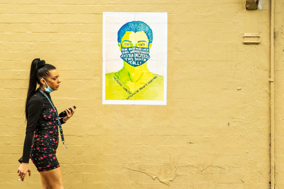 A woman is seen walking past a political poster in Sydney, Australia. 