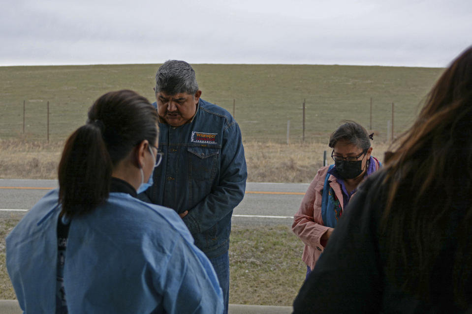 In this Thursday, April 29, 2021, photo, Sherry Cross Child and Shane Little Bear, residents of Stand Off, Alberta, recite a prayer ahead of a vaccination clinic held in Montana for Canadian residents at the Piegan-Carway border crossing near Babb, Mont. The Blackfeet tribe gave out surplus vaccines to its First Nations relatives and others from across the border. (AP Photo/Iris Samuels)