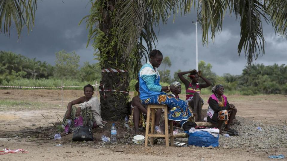 People suffering from the Ebola virus sit under a tree at Makeni Arab Holding Centre in Makeni, Sierra Leone (AP)