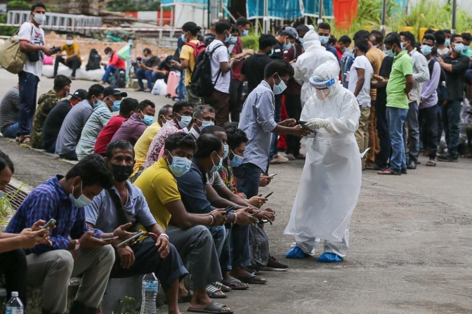 Foreign workers are seen waiting outside the Covid-19 Assessment Centre at the Malawati Stadium in Shah Alam July 14, 2021. — Picture by Yusof Mat Isa