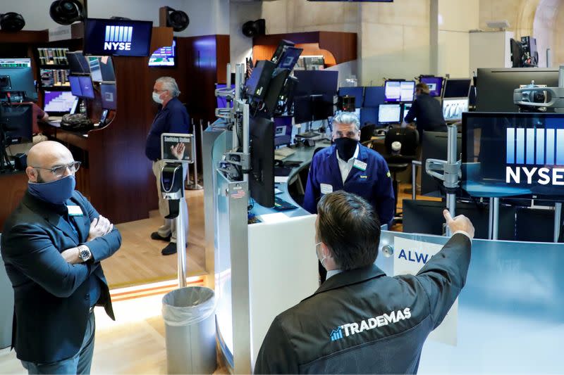 FILE PHOTO: Traders wearing masks work, on the first day of in person trading since the closure during the outbreak of the coronavirus disease (COVID-19) on the floor at the NYSE in New York