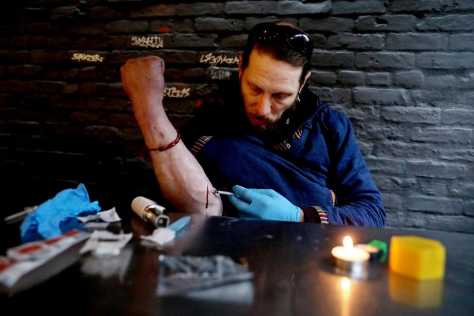 A man with a syringe sits at a table