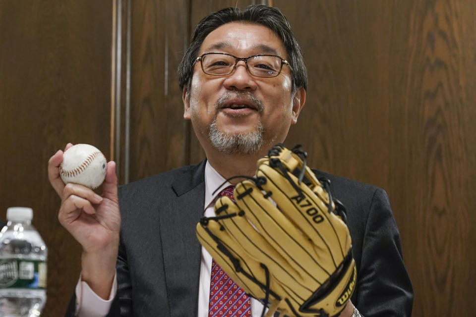 Consul General of Japan in New York Mikio Mori picks up a baseball and glove during a news conference at his residence in New York, Wednesday, April 27, 2022. Ambassador Mori will be throwing out the first pitch at a baseball game to celebrate Japanese heritage and promote the first Japan Parade which will take place in New York on Saturday, May 14, 2022. (AP Photo/Seth Wenig)