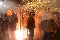 Participants wearing motorcycle helmets get sprayed with firecrackers, during the 'Beehive Firecrackers' festival at the Yanshui district in Tainan