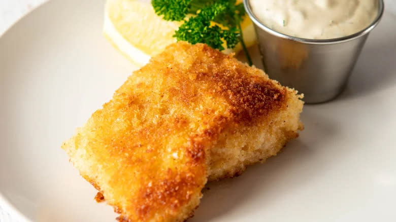 Crumbed fried fish with tartar sauce and lemon wedge