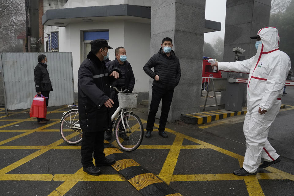 A worker in protective gear holds up a thermometer at the entrance to the Hubei Center for Disease Control and Prevention where a World Health Organization team is making a field visit in Wuhan in central China's Hubei province Monday, Feb. 1, 2021. The WHO mission team investigating the origins of the coronavirus pandemic in Wuhan. (AP Photo/Ng Han Guan)