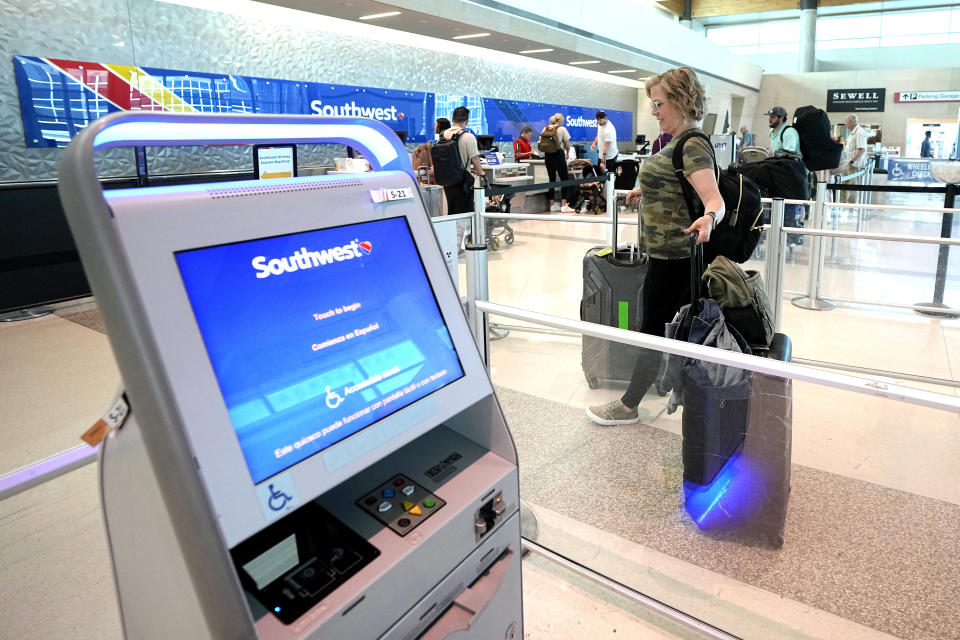 Bethany Adleta, center, of Frisco, Texas, makes her way to the ticketing gate as she prepares to travel out of Love Field airport, Friday, May 19, 2023, in Dallas. Fees, higher fares and fewer discounts for military veterans are causing Adleta to debate flying versus driving if she makes any more trips this summer. (AP Photo/Tony Gutierrez)