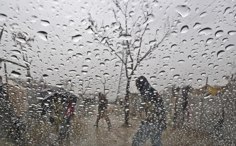 Seen through a car's windshield, Pakistani men run for shelter during rainfall in a slum in Islamabad, Pakistan, Thursday, Feb. 6, 2014. (AP Photo/Muhammed Muheisen)