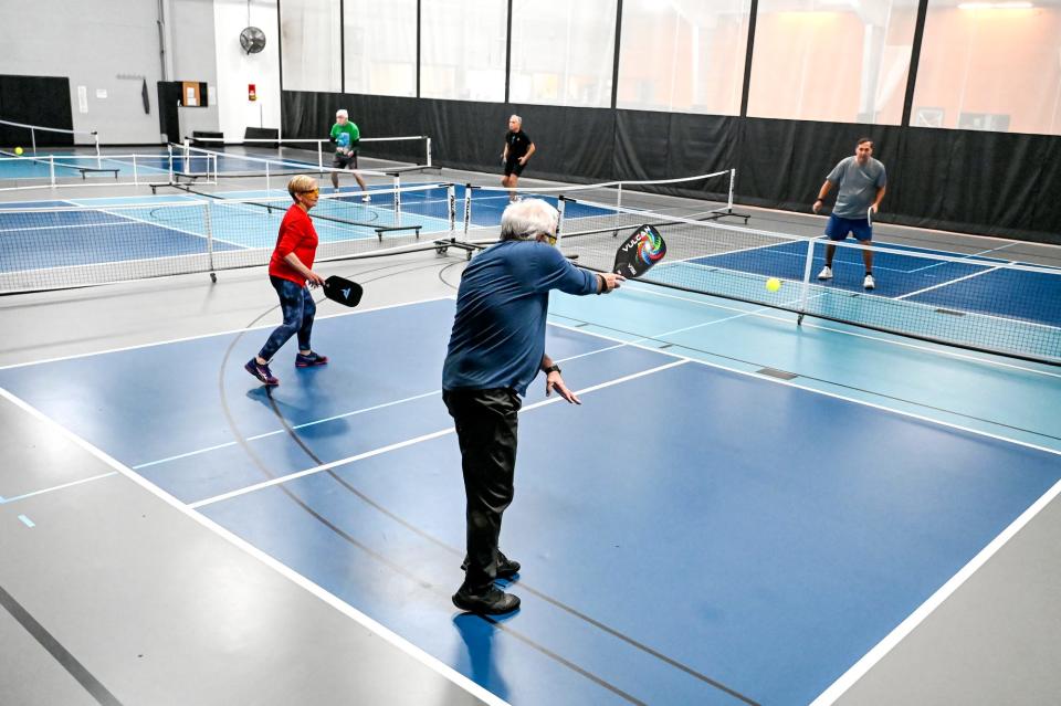 Mike Shore, center, returns the ball during a pickleball game on Friday, Jan. 27, 2023, at Court One Athletic Clubs in Lansing.