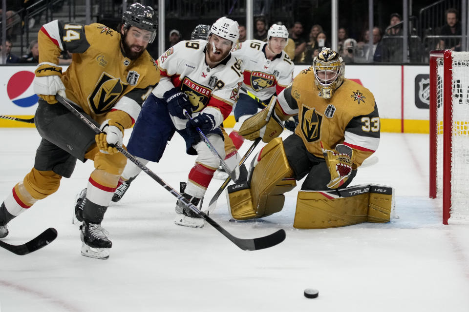Vegas Golden Knights defenseman Nicolas Hague (14) and Florida Panthers left wing Matthew Tkachuk (19) chase down the puck during the first period of Game 2 of the NHL hockey Stanley Cup Finals, Monday, June 5, 2023, in Las Vegas. (AP Photo/John Locher)