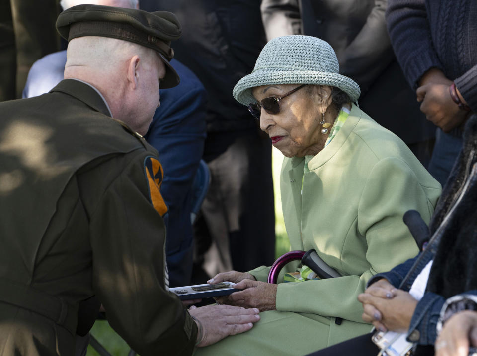 First Army's Command Sgt. Maj. Chris Prosser, left, presents Joann Woodson with her husband's Combat Medic Badge during a posthumous medal ceremony at Arlington National Cemetery on Tuesday, Oct. 11, 2023 in Arlington, Va. During the D-Day invasion, the landing craft Cpl. Waverly B. Woodson Jr was in took heavy fire and he was wounded before even getting to the beach, but for the next 30 hours he treated 200 wounded men while under intense small arms and artillery fire before collapsing from his injuries and blood loss, according to accounts of his service. (AP Photo/Kevin Wolf)