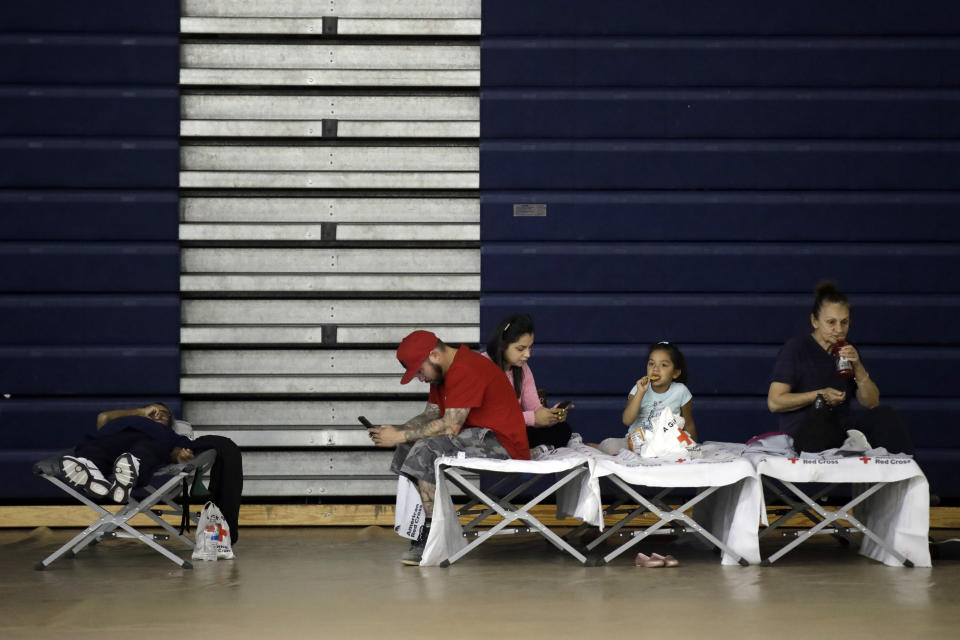 Evacuees from the Tick Fire sit on cots inside the gym at West Ranch High School Friday, Oct. 25, 2019, in Santa Clarita, Calif. (AP Photo/Marcio Jose Sanchez)