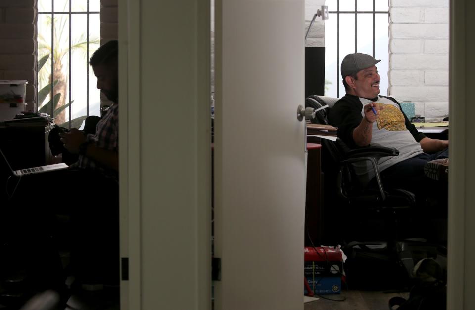 A man sitting at a desk in an office as seen through an open door