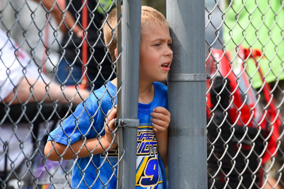 A young fan looks on between a fence prior to the NASCAR Camping World Truck Series United Rentals 176 at Watkins Glen International on Aug. 7, 2021.