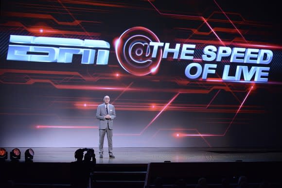 A man standing on stage in front of a screen that says ESPN @ The Speed of Live