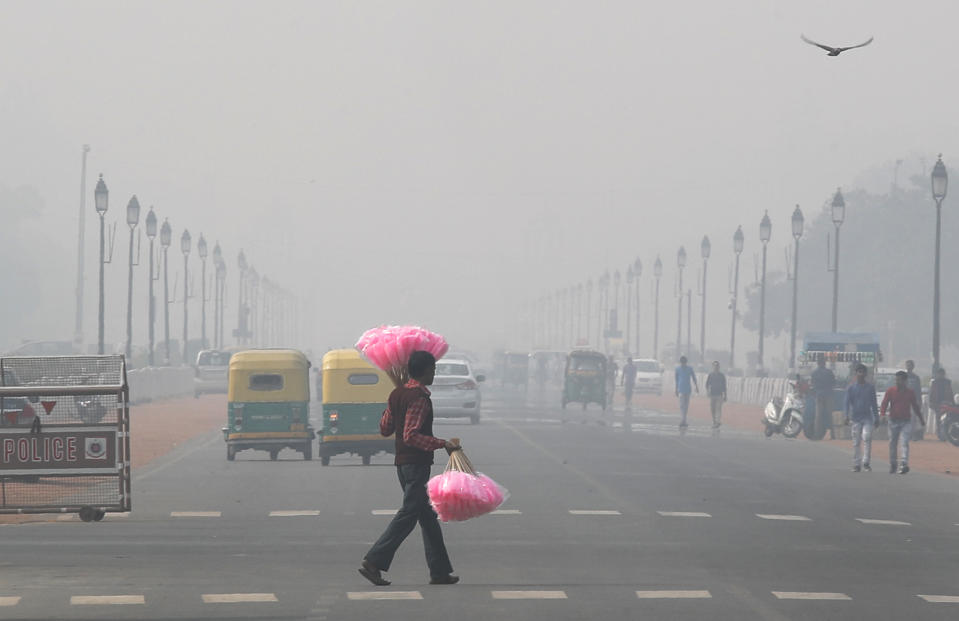 A sweet candy vendor walks amidst thick layer of smog as he looks for customers in New Delhi, India, Tuesday, Nov. 12, 2019. A thick haze of polluted air is hanging over India's capital, with authorities trying to tackle the problem by sprinkling water to settle dust and banning some construction. The air quality index exceeded 400, about eight times the recommended maximum. (AP Photo/Manish Swarup)