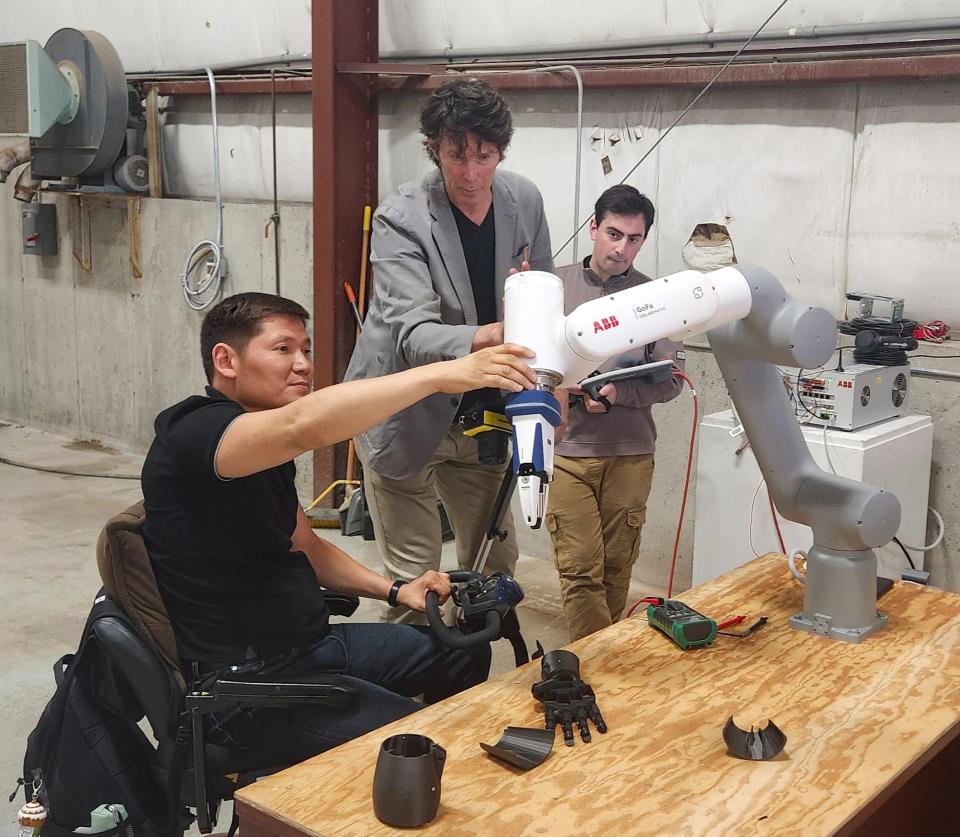 Kyrgyzstani delegate Mirbek Asangariev (left) looks at a small-scale robotic arm used for fabrication with New Bedford Research & Robotics founder Mark Parsons and NBRR collaborator Michael Nesralla.