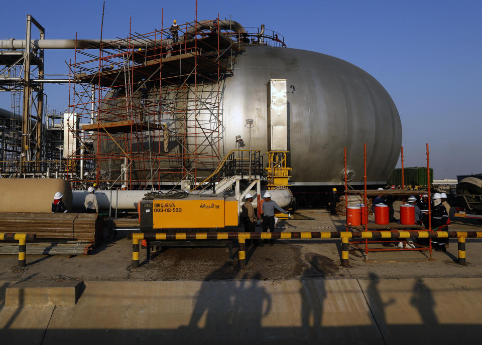 During a trip organized by Saudi information ministry, shadows of cameramen are reflected as workers fix a hole in Aramco's oil separator at processing facility after the recent Sept. 14 attack on Aramco's oil processing facility in Abqaiq, near Dammam in the Kingdom's Eastern Province, Friday, Sept. 20, 2019. Saudi Arabia allowed journalists access Friday to the site of a missile-and-drone attack on a facility at the heart of the kingdom's oil industry, an assault that disrupted global energy supplies and further raised tensions between the U.S. and Iran. (AP Photo/Amr Nabil)