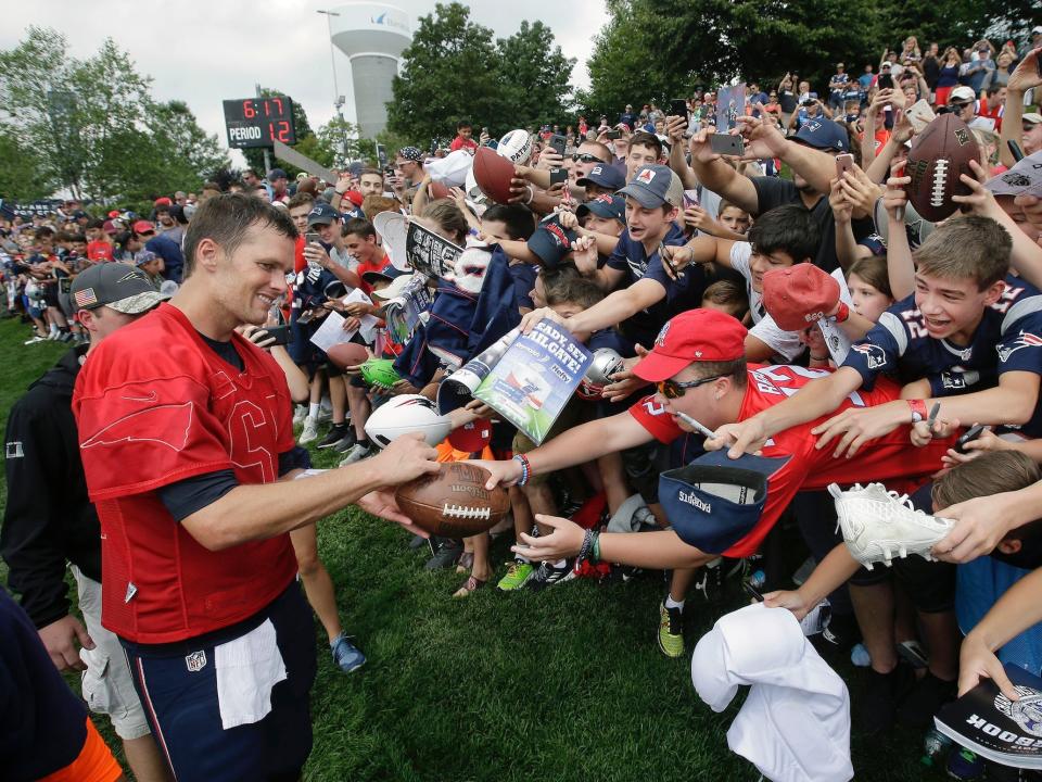 Tom Brady signs autographs in front of a crowd of fans at Patriots training camp in 2017.