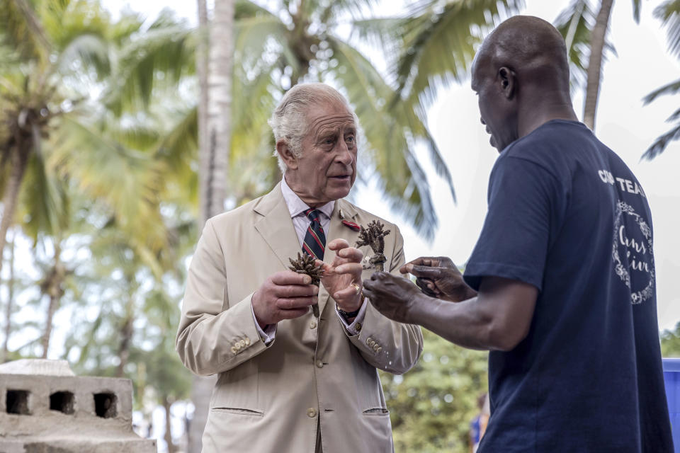 Britain's King Charles III, left, prepares to plant coral on a concrete block to be dropped in the sea, at the coral restoration project during a visit to Kuruwitu Conservation Area in Kilifi, Kenya, Thursday, Nov. 2, 2023. (Luis Tato/Pool Photo via AP)