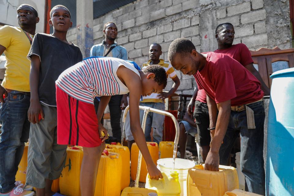 Residents fill their containers with potable water, in Port-au-Prince, Haiti, Friday, March 8, 2024. (AP Photo/Odelyn Joseph)