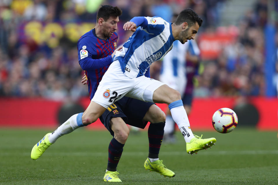 Espanyol's Mario Hermoso, right, beats Barcelona's Lionel Messi to the ball during a Spanish La Liga soccer match between FC Barcelona and Espanyol at the Camp Nou stadium in Barcelona, Spain, Saturday March 30, 2019. (AP Photo/Manu Fernandez)