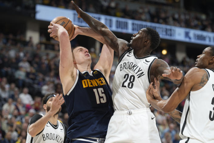 Denver Nuggets center Nikola Jokic, second from left, drives the basket past, from left to right, Brooklyn Nets guard Seth Curry, forward Dorian Finney-Smith and center Nic Claxton in the second half of an NBA basketball game Sunday, March 12, 2023, in Denver. (AP Photo/David Zalubowski)