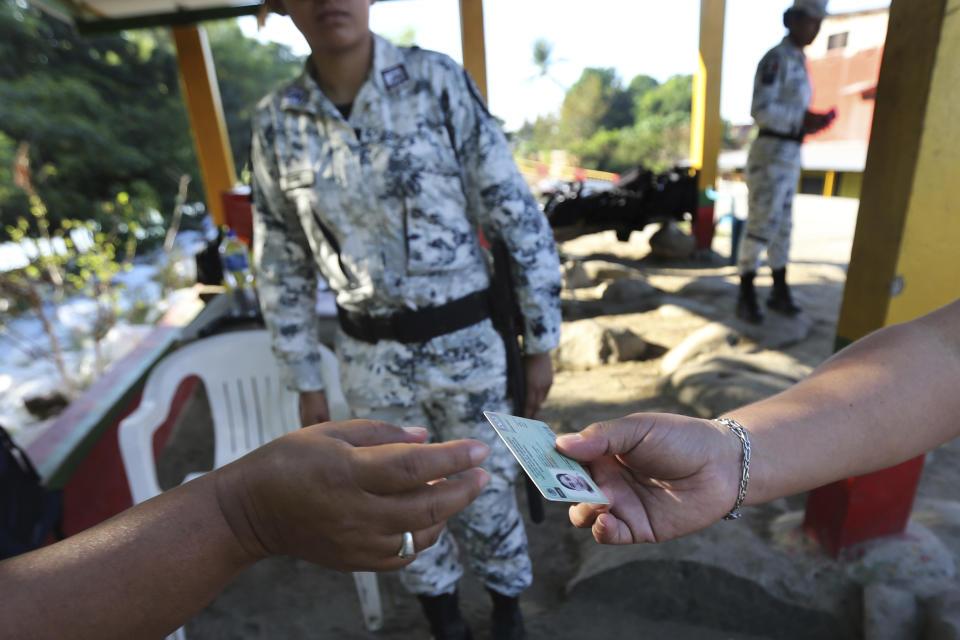 A Mexican National Guardsman checks the identification card of a man near the Suchiate River in Ciudad Hidalgo, on the Mexican border with Guatemala, Sunday, Jan. 19, 2020. Mexican authorities have closed a border entry point in southern Mexico after thousands of Central American migrants tried to push across a bridge between Mexico and Guatemala. (AP Photo / Marco Ugarte)