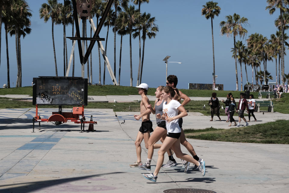 Joggers run along the strand by a closed Venice beach on Friday, July 3, 2020 in Los Angeles. California's governor is urging people to wear masks and skip Fourth of July family gatherings as the state's coronavirus tally rises. But Gov. Gavin Newsom on Thursday said he'd rely on people using common sense rather than strict enforcement of the face-covering order. Rates of COVID-19 infections and hospitalizations have soared in the past two weeks after falling last month. (AP Photo/Richard Vogel)