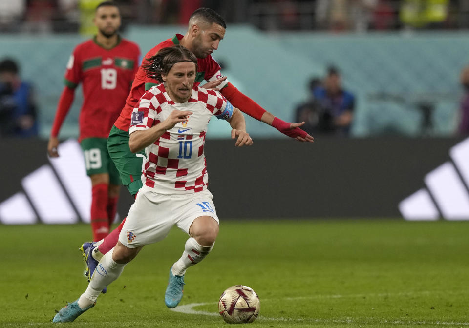 Croatia's Luka Modric, front, duels for the ball with Morocco's Hakim Ziyech during the World Cup third-place playoff soccer match between Croatia and Morocco at Khalifa International Stadium in Doha, Qatar, Saturday, Dec. 17, 2022. (AP Photo/Frank Augstein)