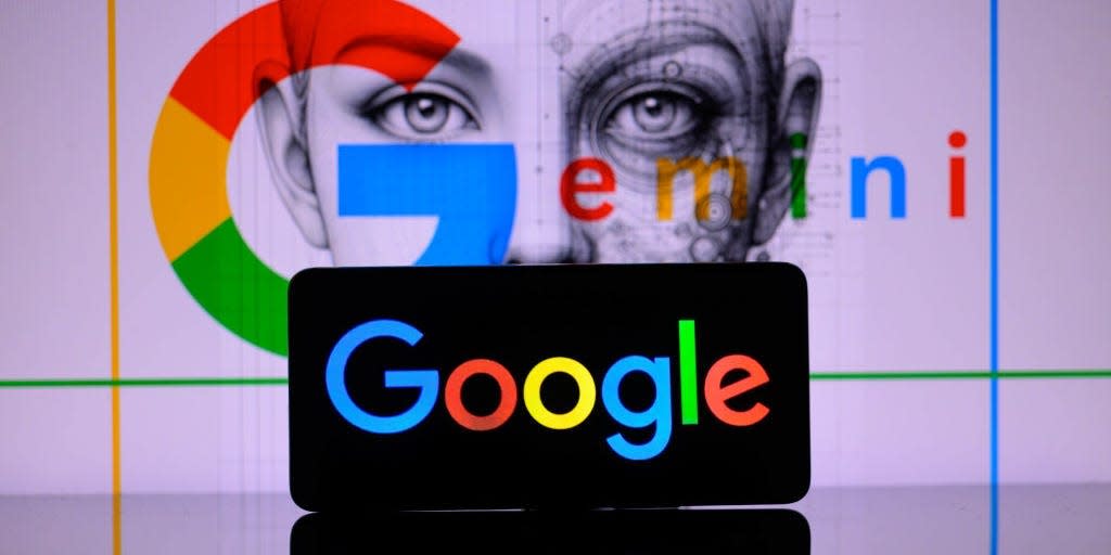 A smartphone displaying the Google logo sits in front of a backdrop with the Gemini logo.