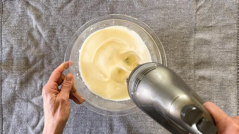 Whipping cream in mixing bowl with hand mixer 