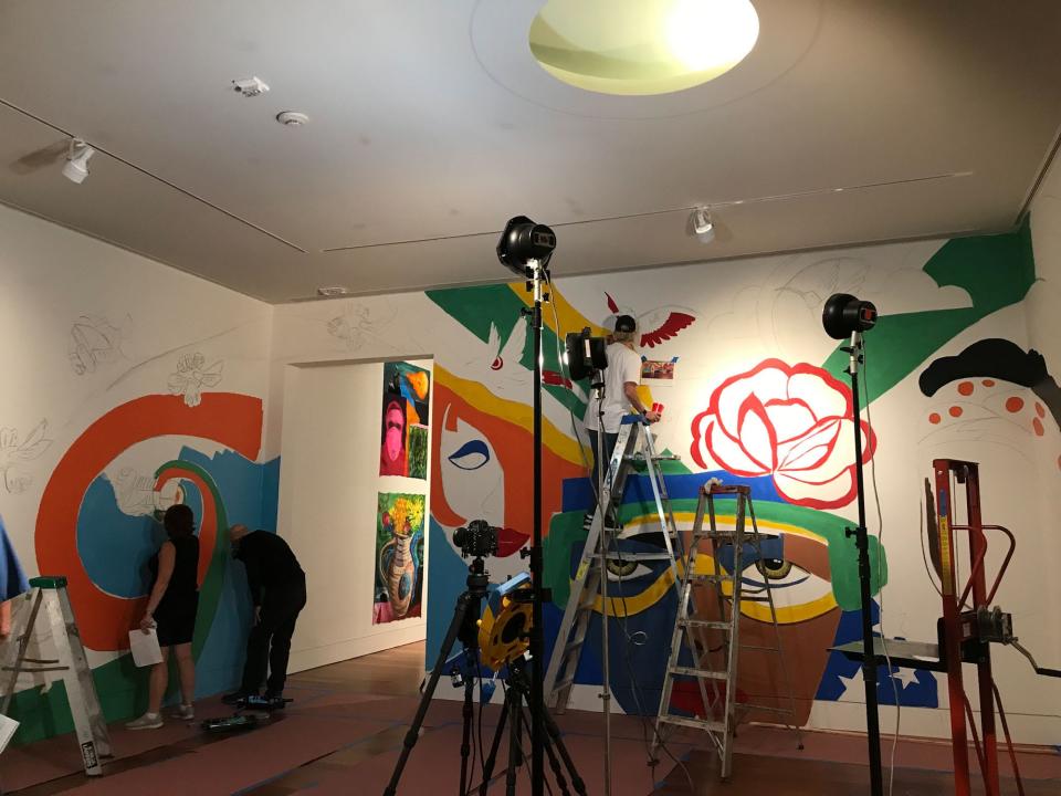 Assistants of Charlotte artist Rosalia Torres-Weiner paint a mural for "Lugar de Encuentros/Place of Encounters," a new exhibition at the Cameron Art Museum.