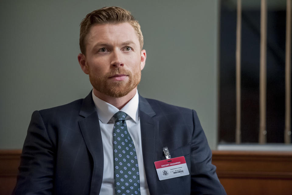 Close-up of Sam in a suit and tie and wearing a name tag