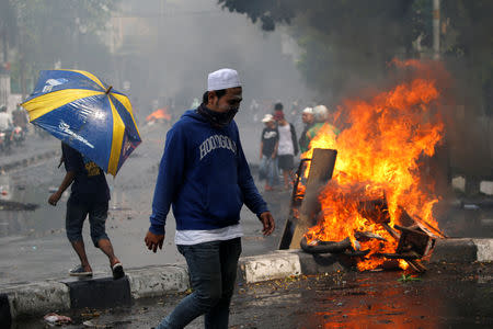Men walk past burning tires during a protest following the announcement of last month's election official results in Jakarta, Indonesia, May 22, 2019. REUTERS/Willy Kurniawan