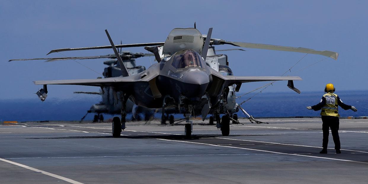 A crew member makes a signal to F-35 aircraft for take off on the UK's aircraft carrier HMS Queen Elizabeth in the Mediterranean Sea on June 20, 2021.