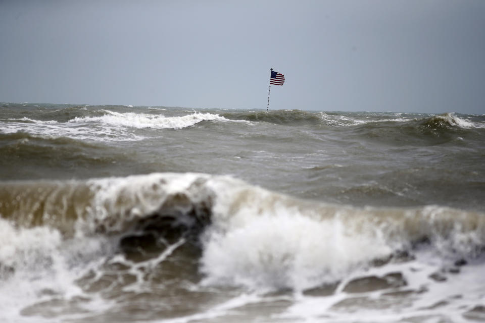 Waves crash in front of an American flag that is planted on a jetty during a high surf from the Atlantic Ocean, in advance of the potential arrival of Hurricane Dorian, in Vero Beach, Fla., Monday, Sept. 2, 2019. (AP Photo/Gerald Herbert)