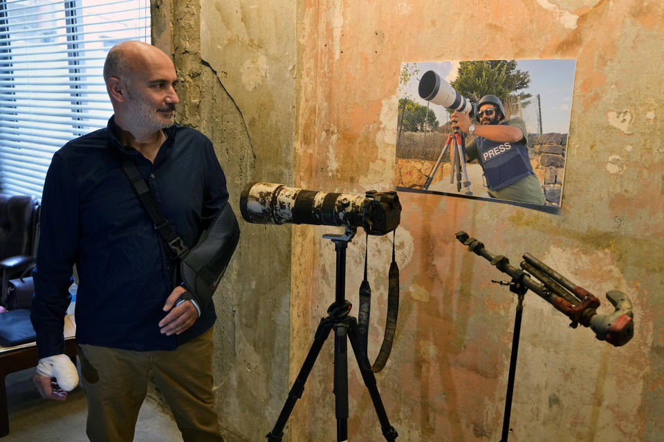 Elie Brakhya, a cameraman with Qatar's Al-Jazeera TV, who was injured when an Israeli shell landed in a gathering of international journalists on Oct. 13, 2023, looks at the poster of Reuters videographer Issam Abdallah who was killed in the same shelling, as he attend a press conference by Amnesty International and Human Rights Watch in Beirut, Lebanon, Thursday, Dec. 7, 2023. Two Israeli strikes that killed a Reuters videographer and wounded six other journalists in south Lebanon nearly two months ago were an apparent deliberate and direct attack on civilians "that must be investigated as a war crime," two international human rights groups said Thursday. (AP Photo/Bilal Hussein)